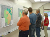 Picture of attendees looking at maps on wall.
